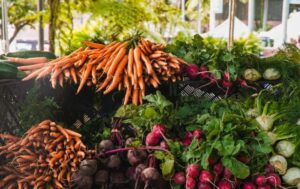 A vibrant display of fresh carrots, radishes, and greens at a local outdoor market.