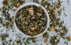 Overhead shot of a cup with a blend of dried herbal tea leaves and flowers.