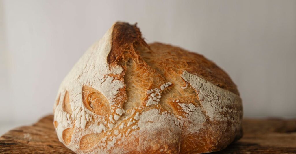 Close-up of freshly baked artisan sourdough bread on a rustic wooden board.