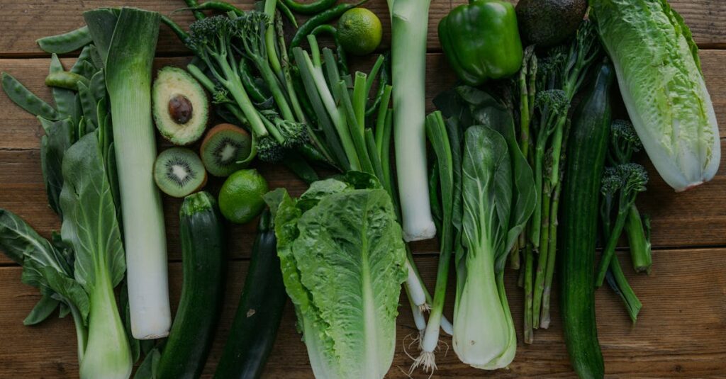 High-angle view of assorted fresh green vegetables arranged on a wooden table.