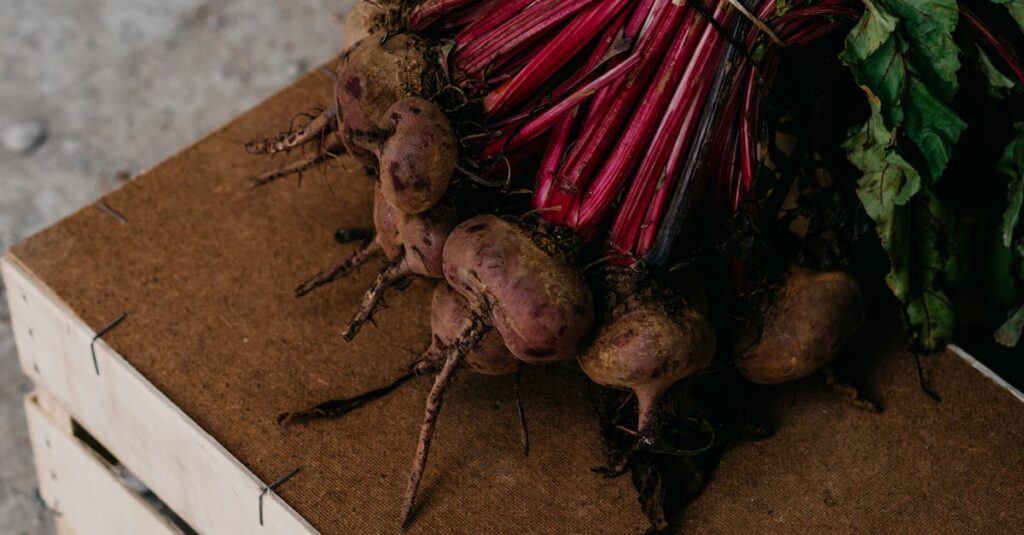 A bunch of fresh organic beetroots with leaves on a rustic wooden crate, showcasing root vegetables.